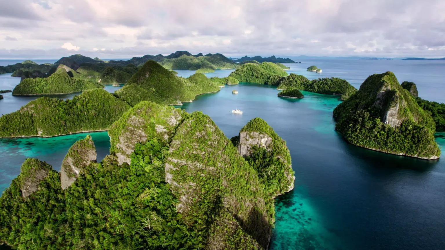 an-aerial-view-showcases-the-stunning-karst-topography-and-turquoise-waters-of-raja-ampat-with-boats-dotting-the-scene-scaled